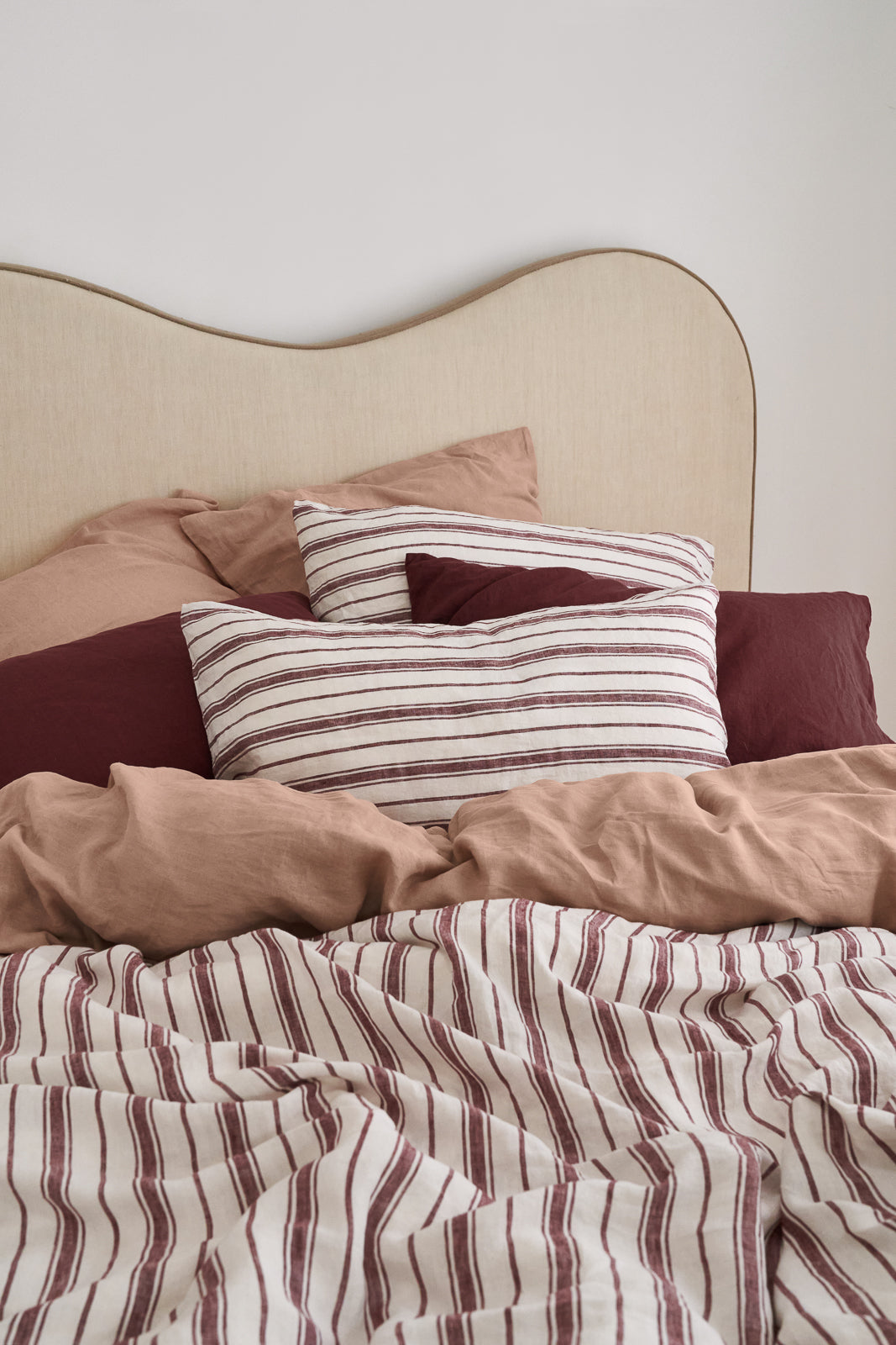 French flax linen sheets in clay, cherrywood, and cherrywood stripe