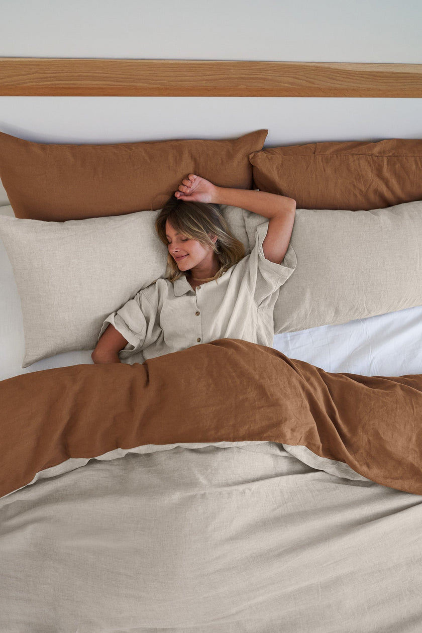 Model asleep with her arm up in hazelnut and natural 100% french flax linens sheets