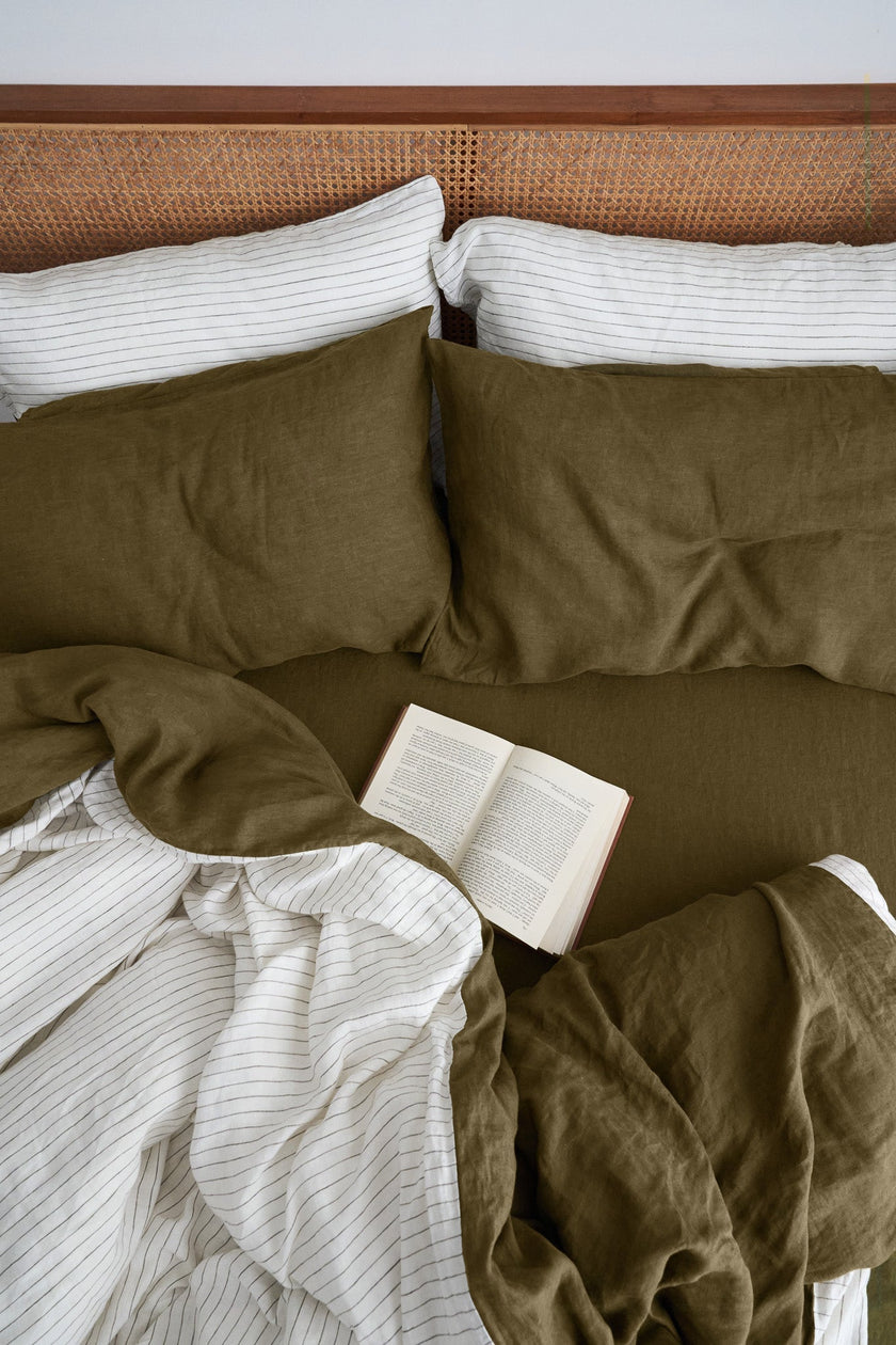Cosy bed with Olive linen sheets and a book